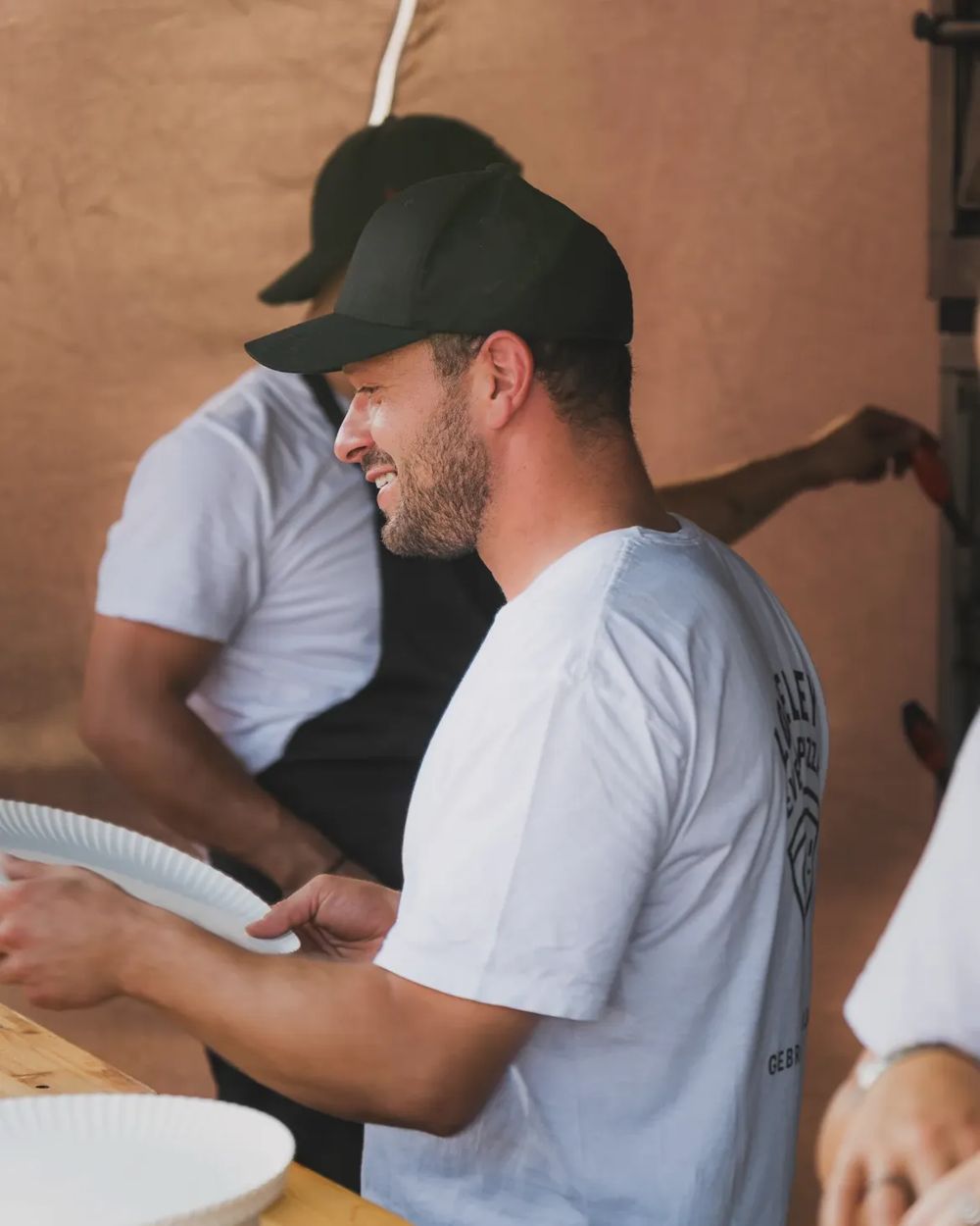 Lachender Mitarbeiter reicht Pizzateller über die Theke